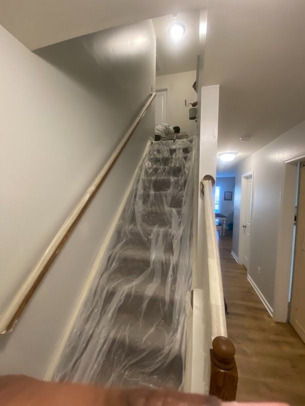 Staircase covered in plastic sheeting in a narrow hallway, suggesting home renovation or cleanup.