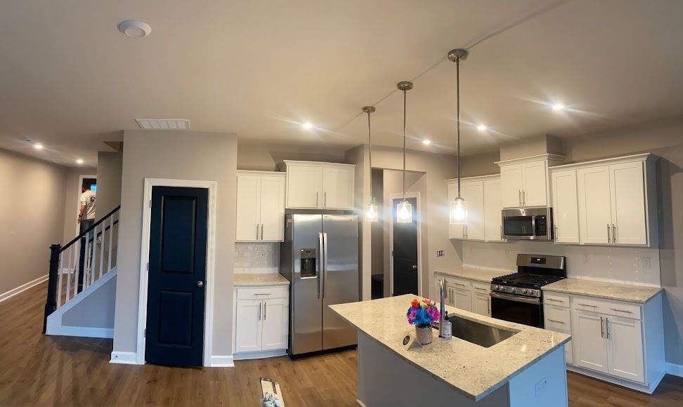 Bright modern kitchen and dining area with white cabinets, island, stainless appliances, and wood floors