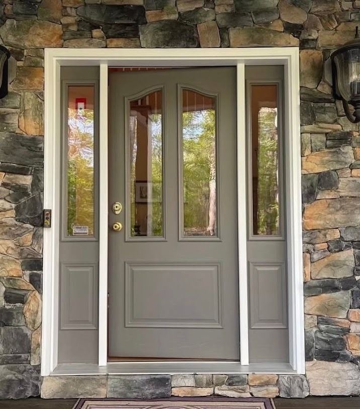 Gray front door with narrow glass panels in a stone exterior wall