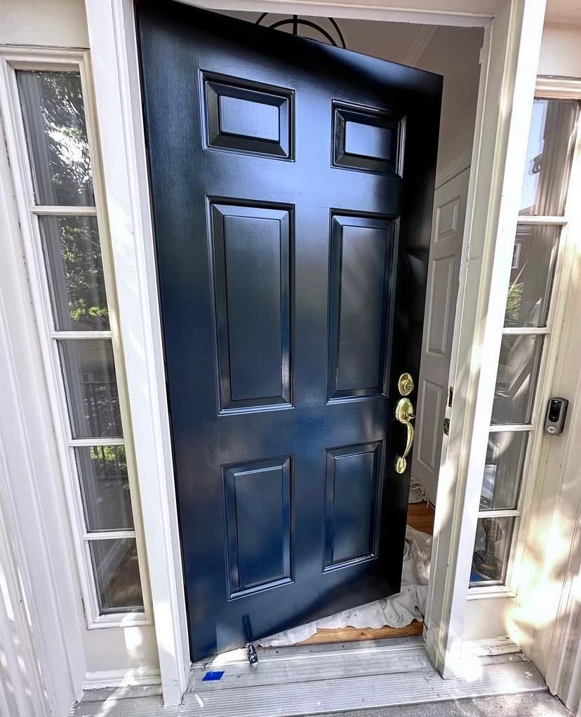 Black front door slightly open, framed by sidelights, with a small step at the entrance.