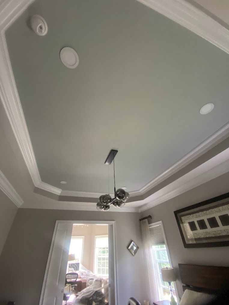 Gray living room ceiling with crown molding, recessed lights, and a hanging chandelier above French doors.