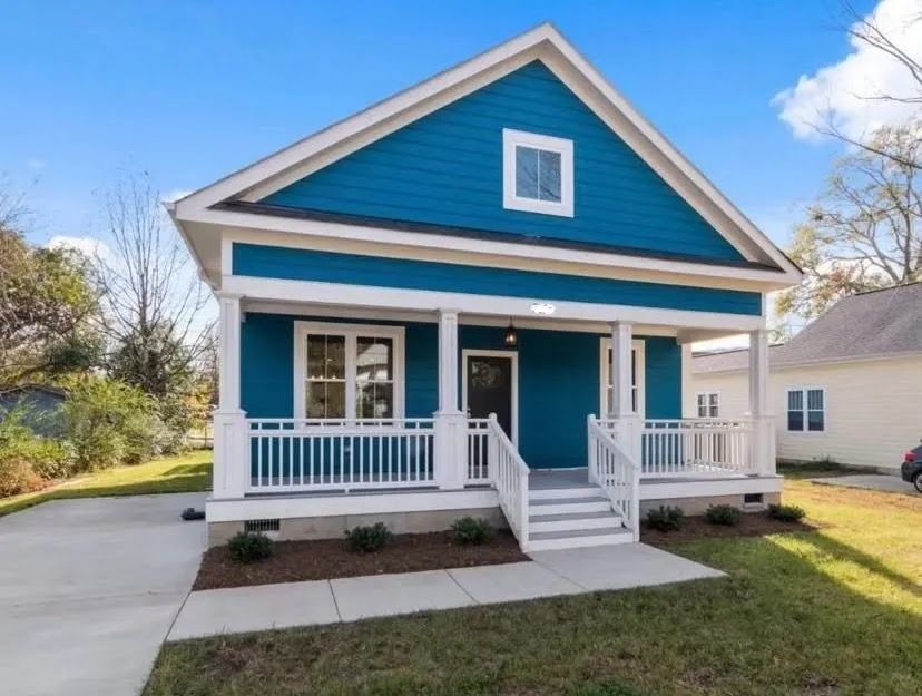 Blue house with white trim and front porch on a sunny suburban street