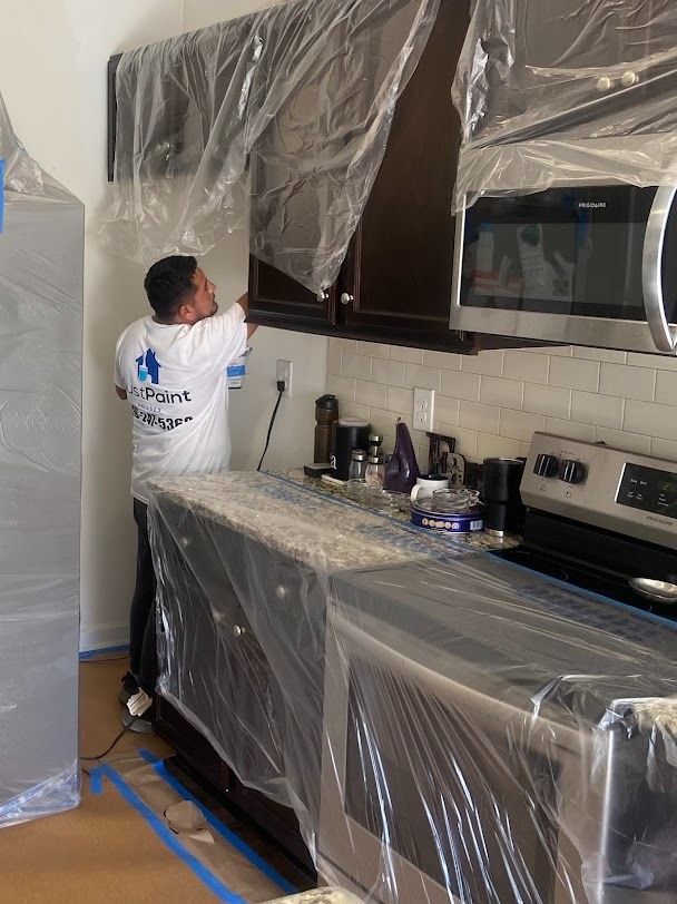 Worker wrapping kitchen cabinets and counters in plastic during renovation