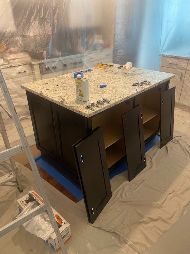 Partially painted black cabinet on a drop cloth, with a speckled countertop in a work area