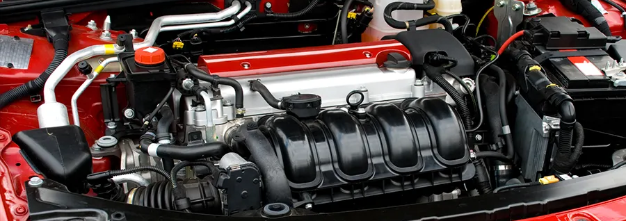 Close-up of a car engine bay with a black intake manifold and red body panels