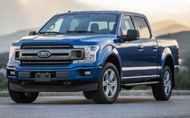 Blue Ford pickup truck on a road with mountains in the background