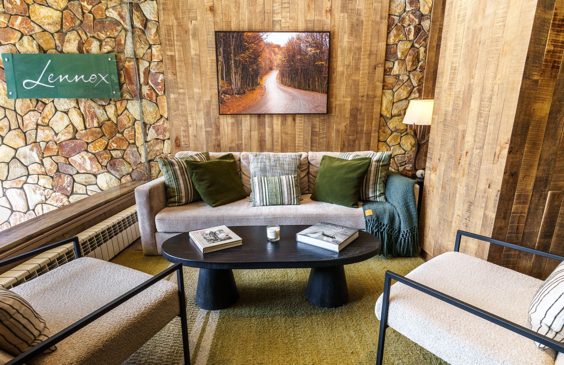 Acogedor salón con sillas de mimbre, sofá gris, mesa de centro y pared decorativa de piedra con obras de arte.
