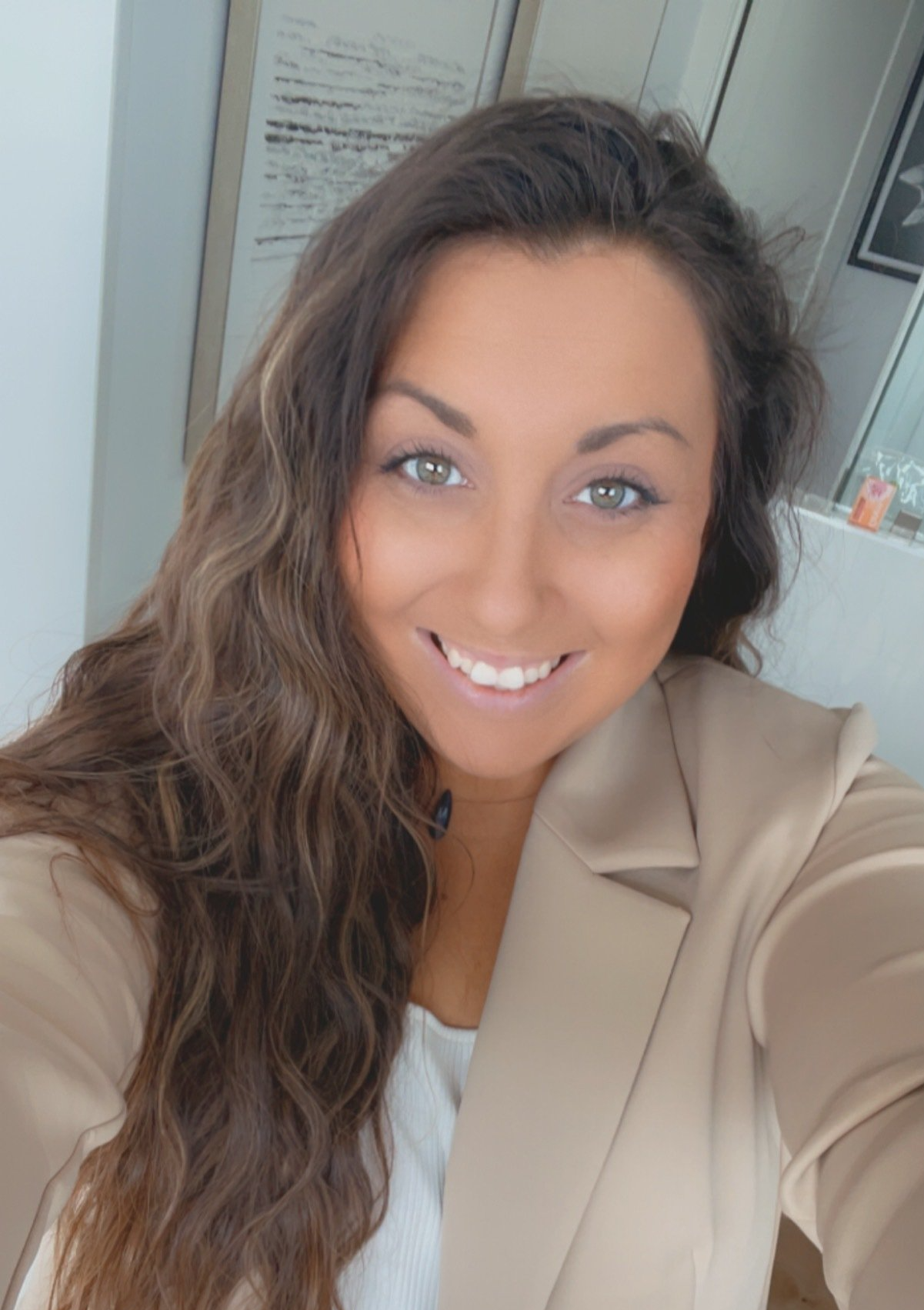 A woman is smiling and taking a selfie in a room.