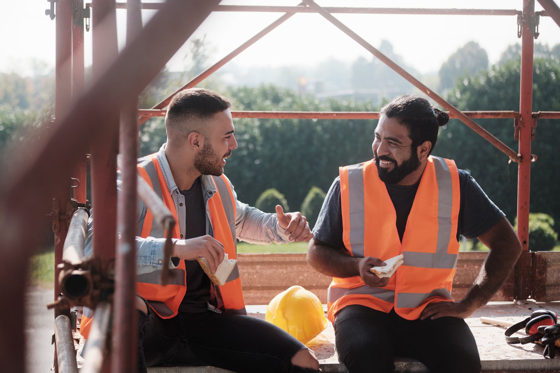 Deux ouvriers du bâtiment sont assis sur un échafaudage et discutent entre eux.