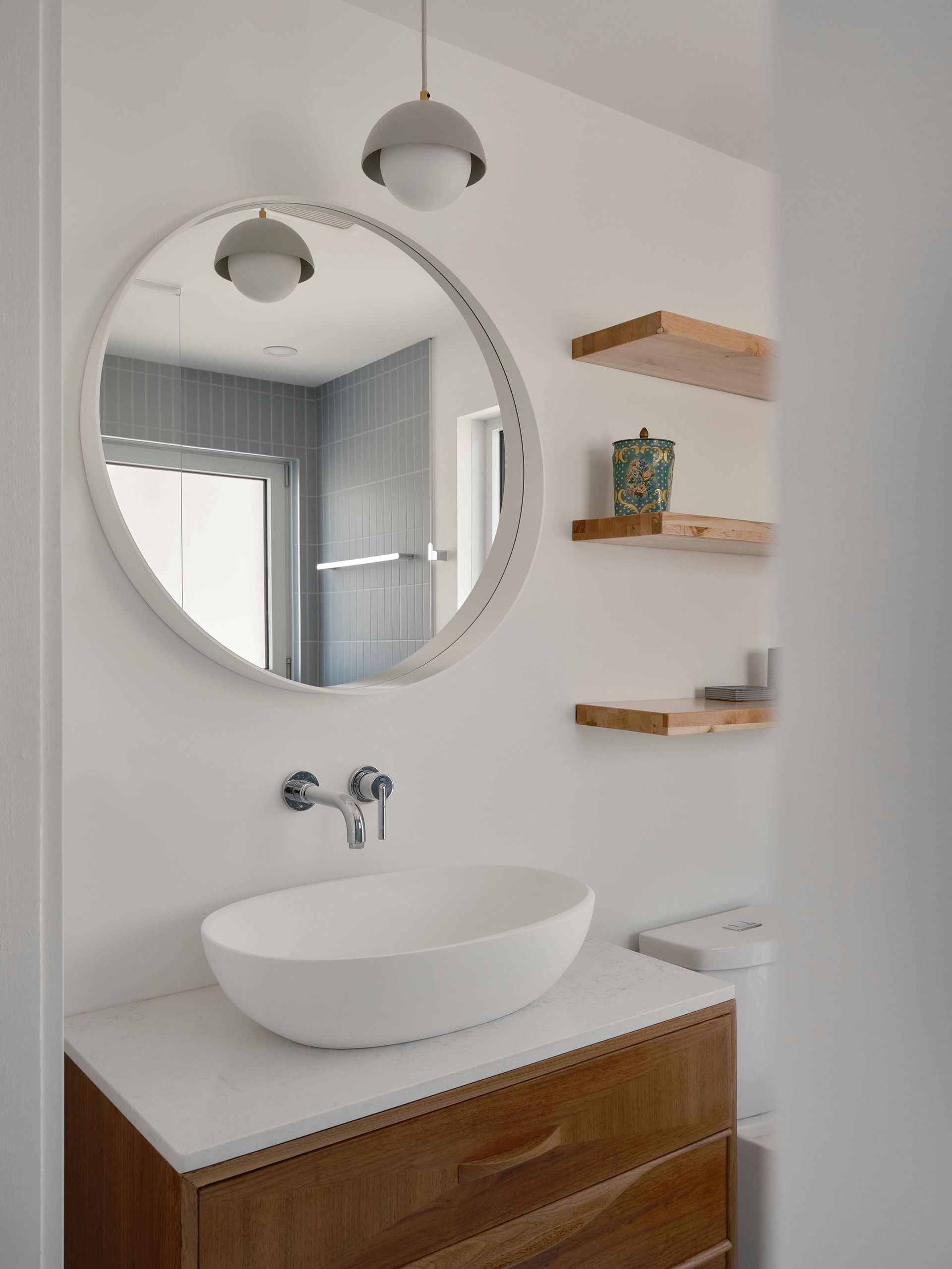 Une salle de bain avec un lavabo, un miroir et des étagères.