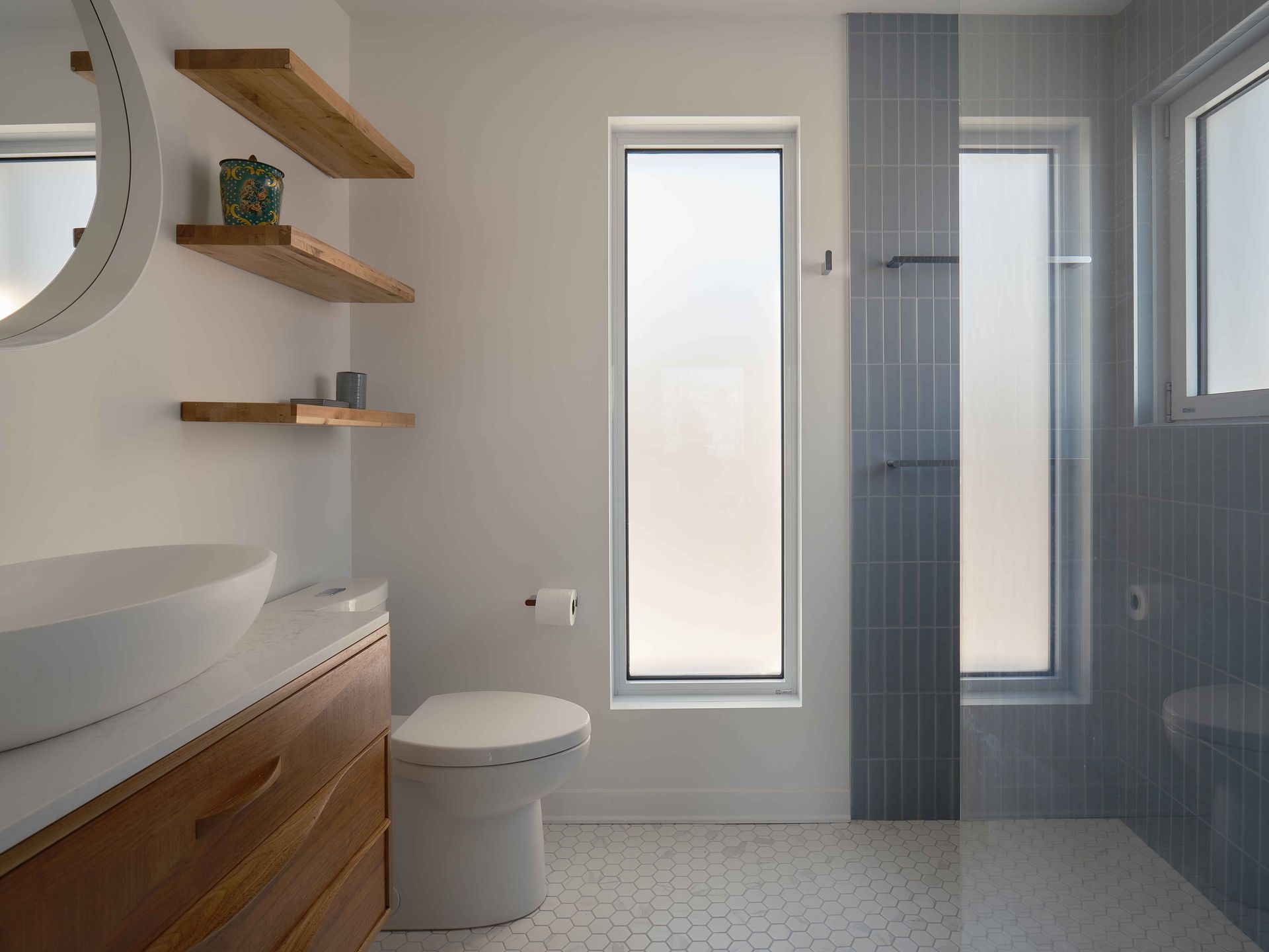 Une salle de bain avec WC, lavabo, miroir et fenêtre.