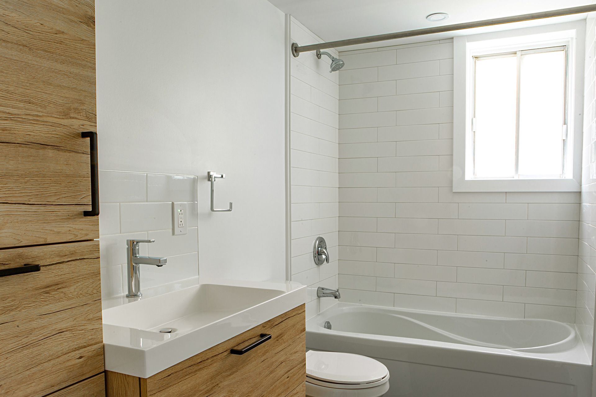 Une salle de bain avec lavabo, toilettes, baignoire et fenêtre.
