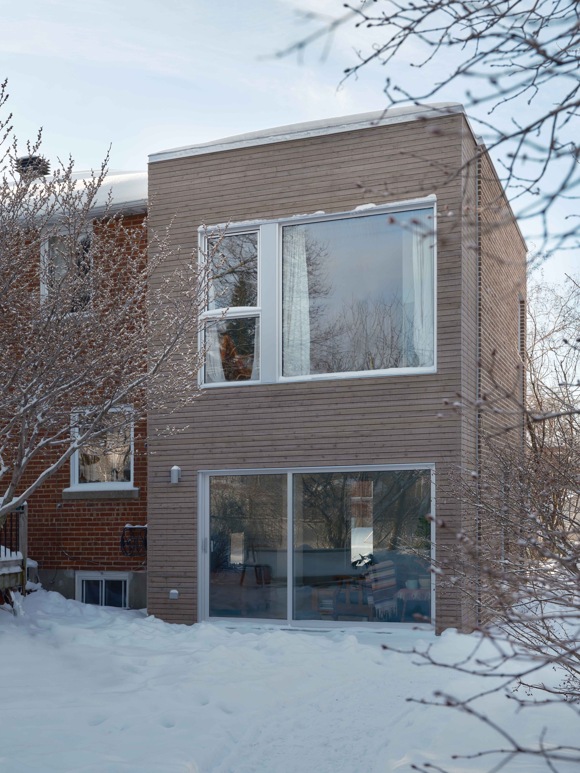 Une maison avec beaucoup de fenêtres est couverte de neige