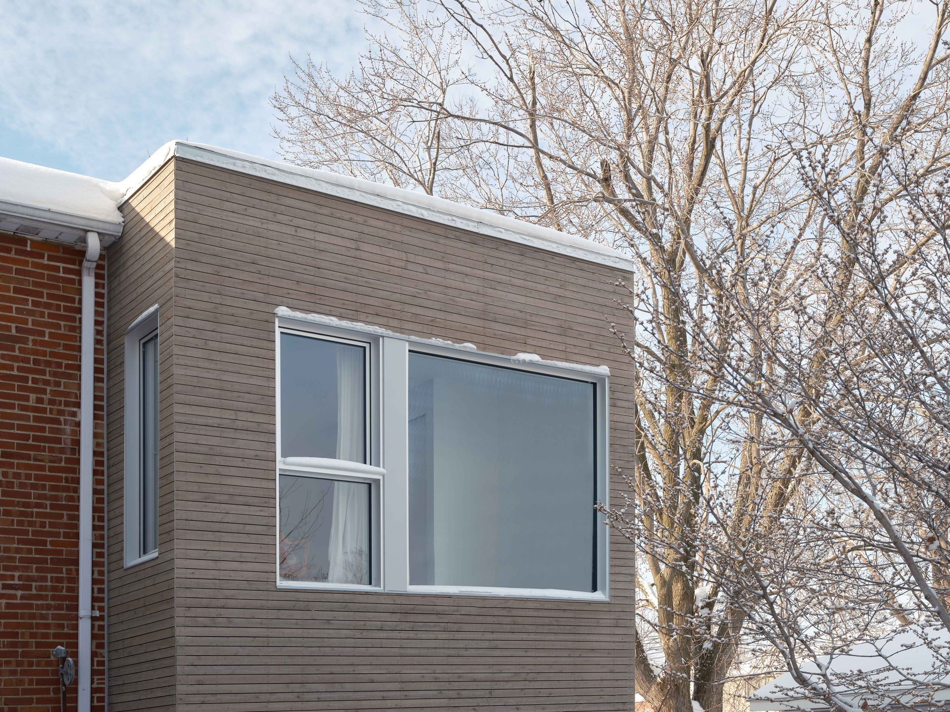 Un bâtiment en briques avec une grande fenêtre et un arbre en arrière-plan.