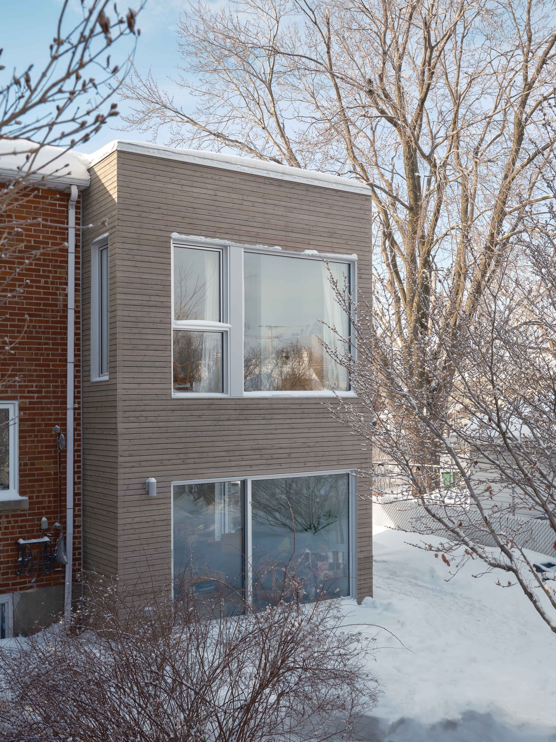 Une maison avec beaucoup de fenêtres est couverte de neige.