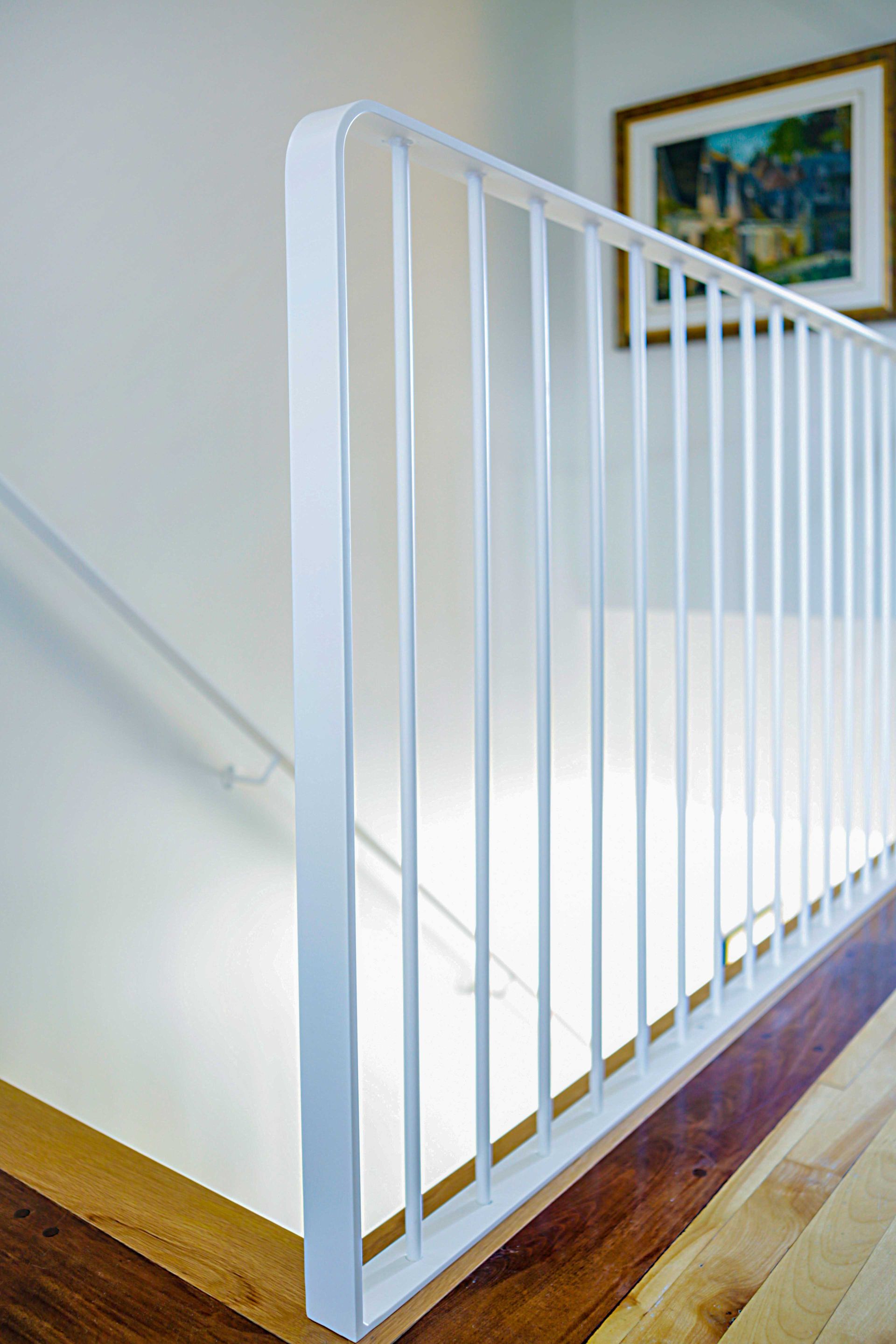 Une rampe blanche sur un escalier avec un tableau sur le mur derrière.