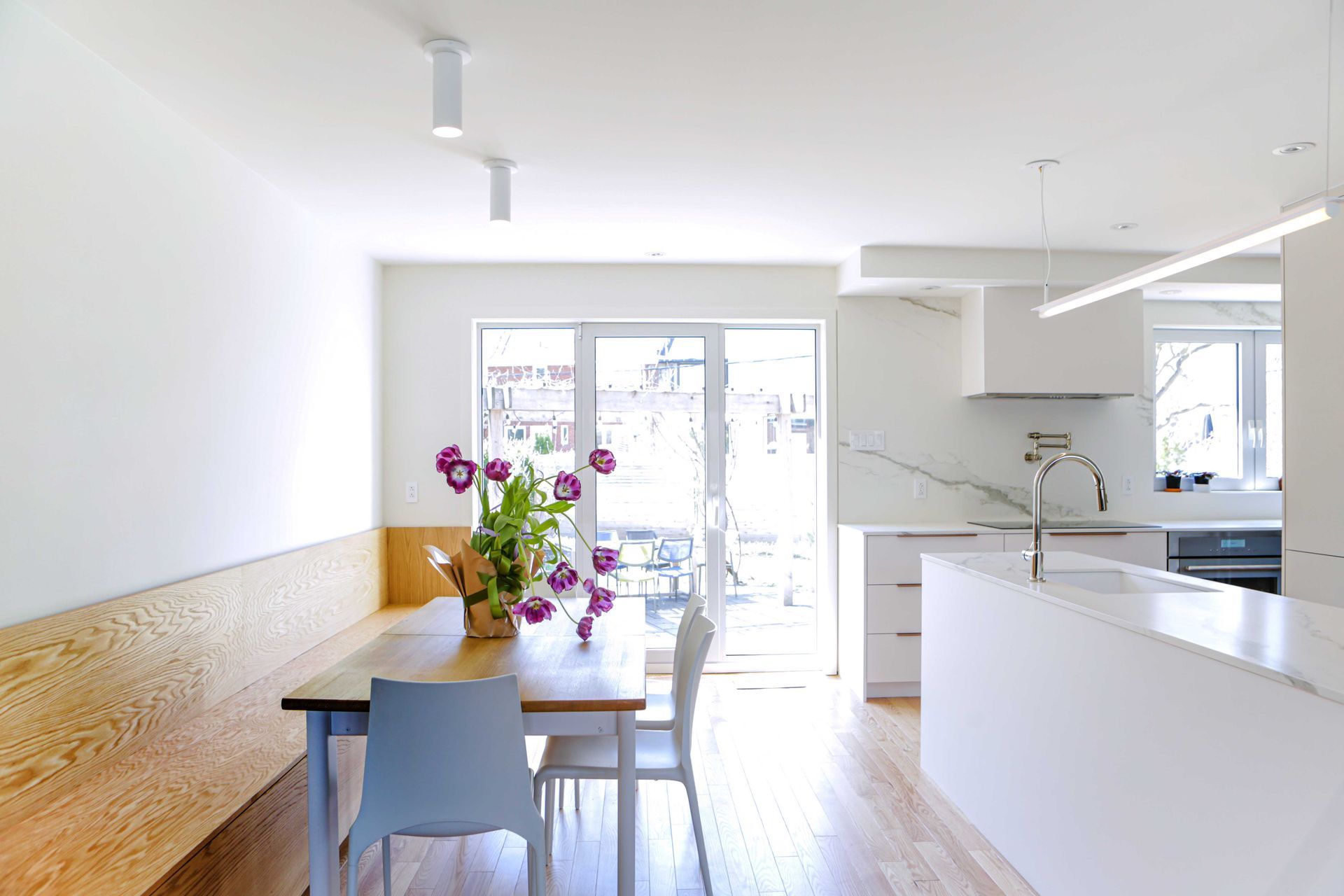 Une cuisine avec une table et des chaises et un vase de fleurs sur la table.