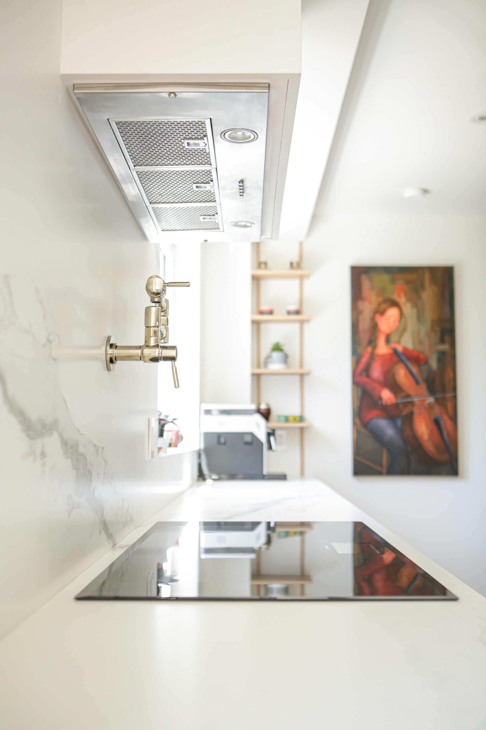 Une cuisine avec une cuisinière et un tableau au mur.