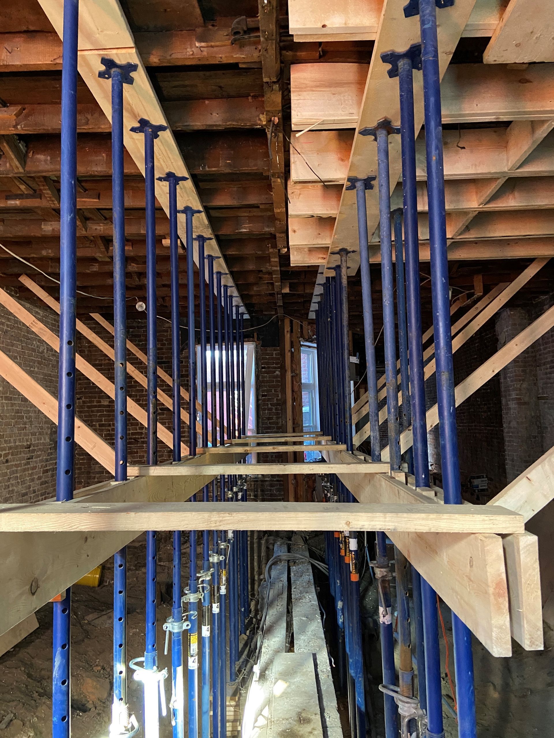 Une rangée d'échafaudages bleus et en bois dans un bâtiment en construction.