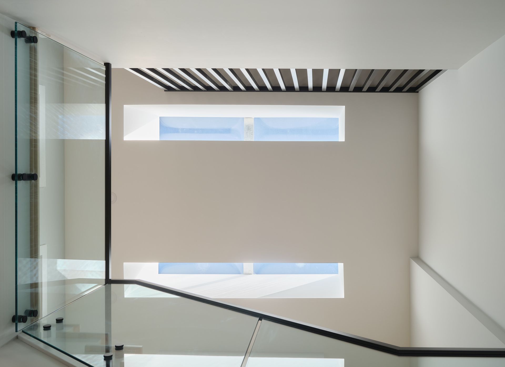 Un escalier avec une rampe en verre et deux fenêtres