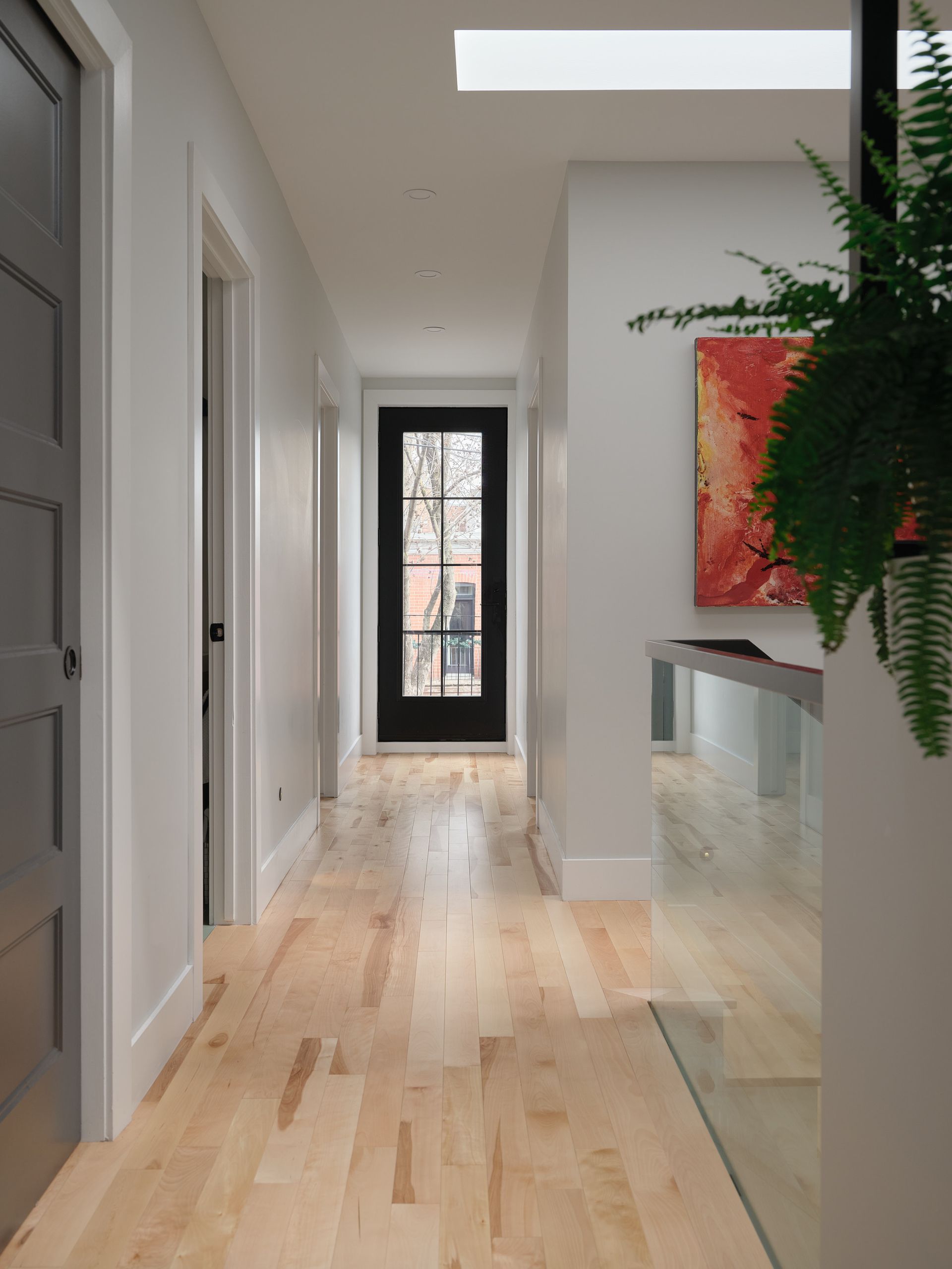 Un couloir avec du parquet et une porte noire