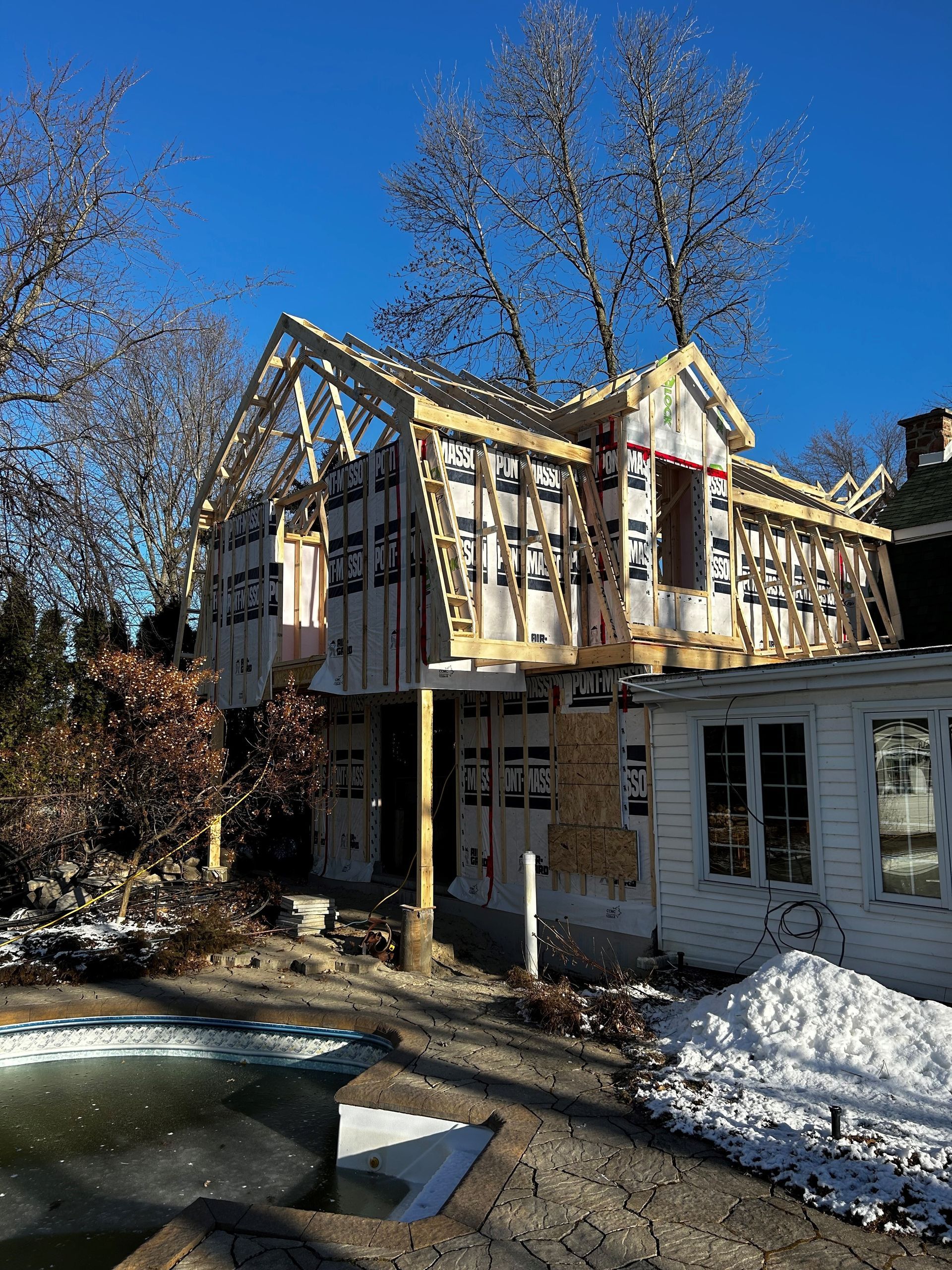 Une maison est en construction dans la neige à côté d'une piscine.