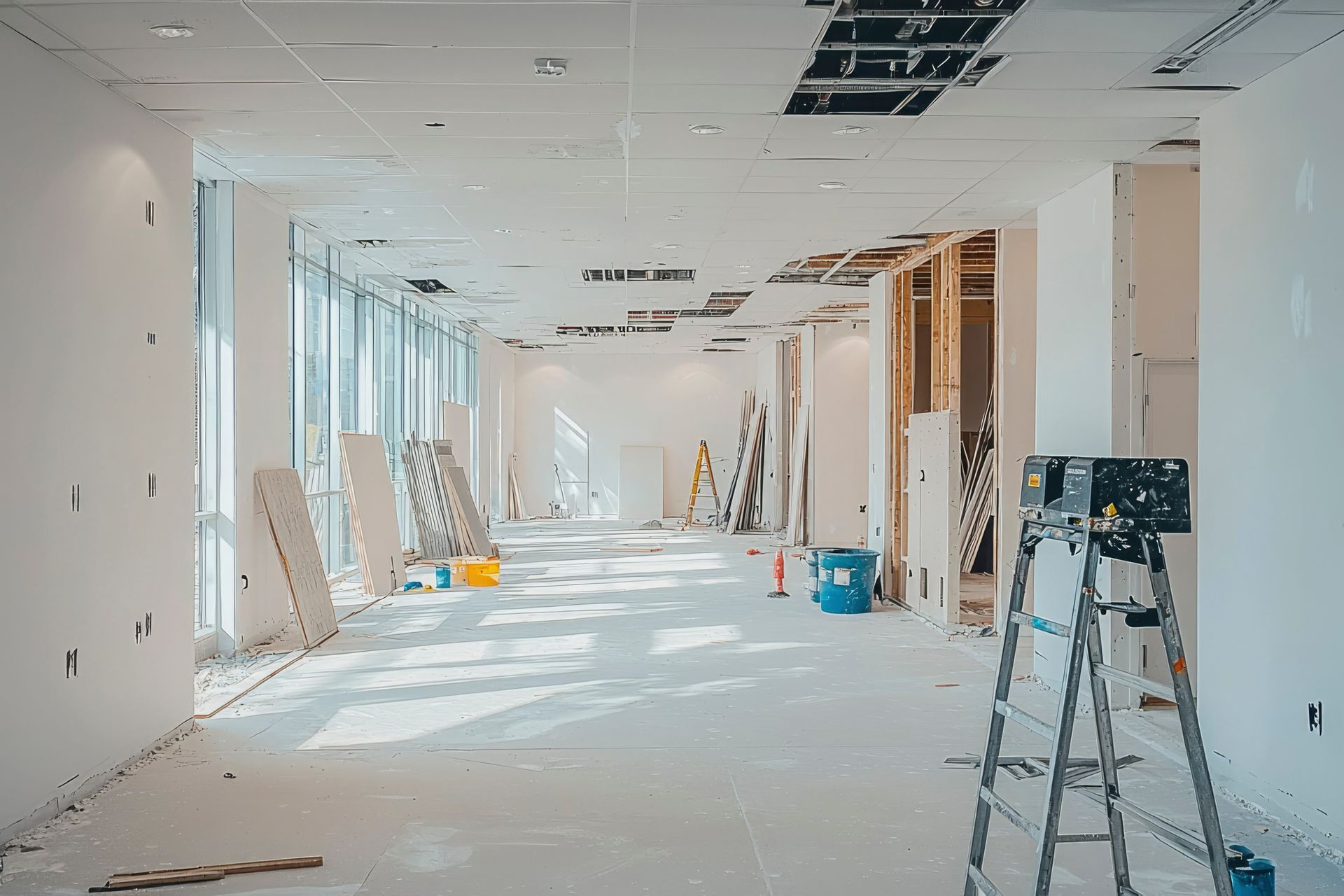 Une échelle est posée au milieu d'une grande pièce en construction.
