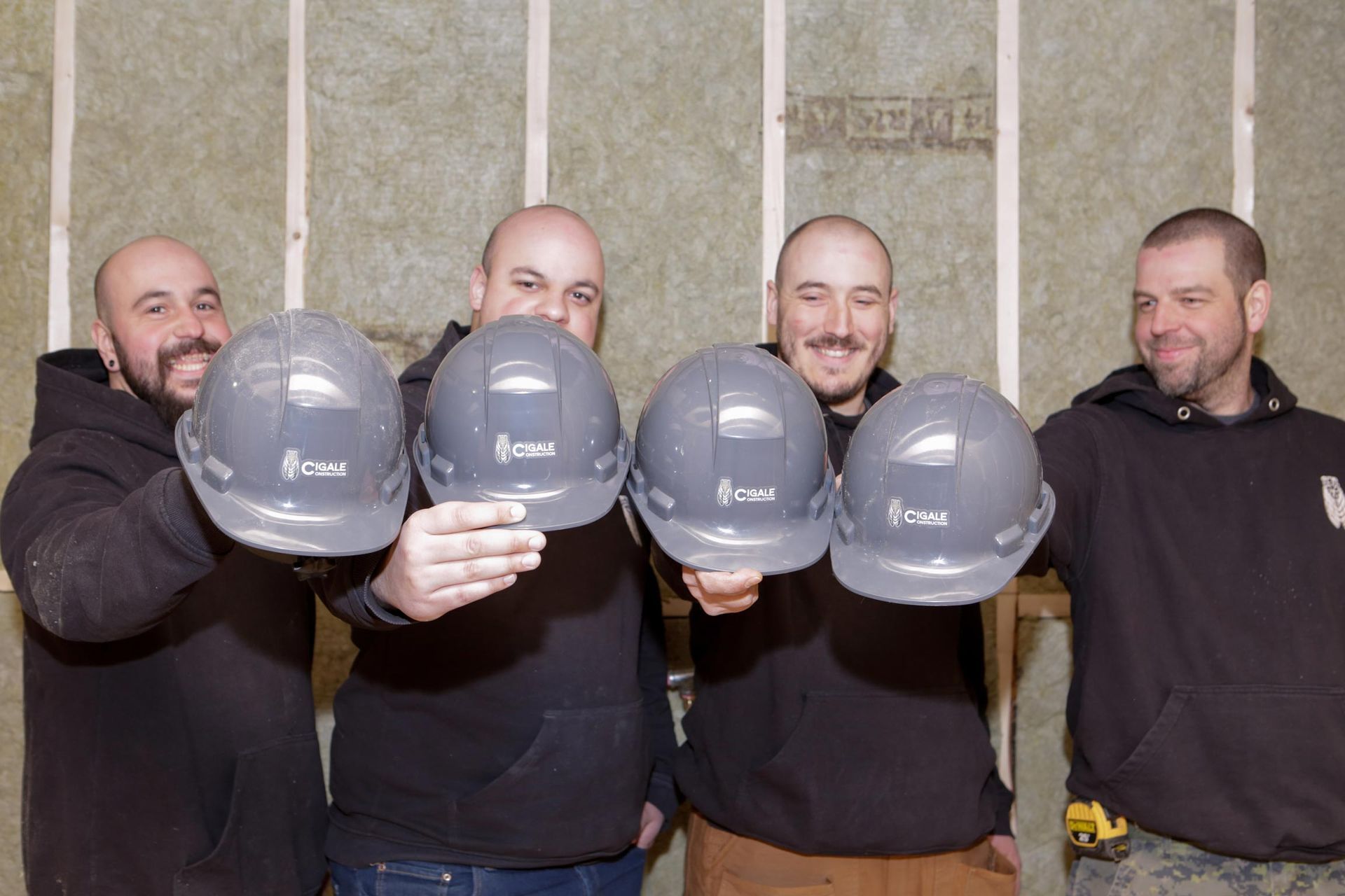 Un groupe d'ouvriers du bâtiment brandissent leurs casques de chantier.