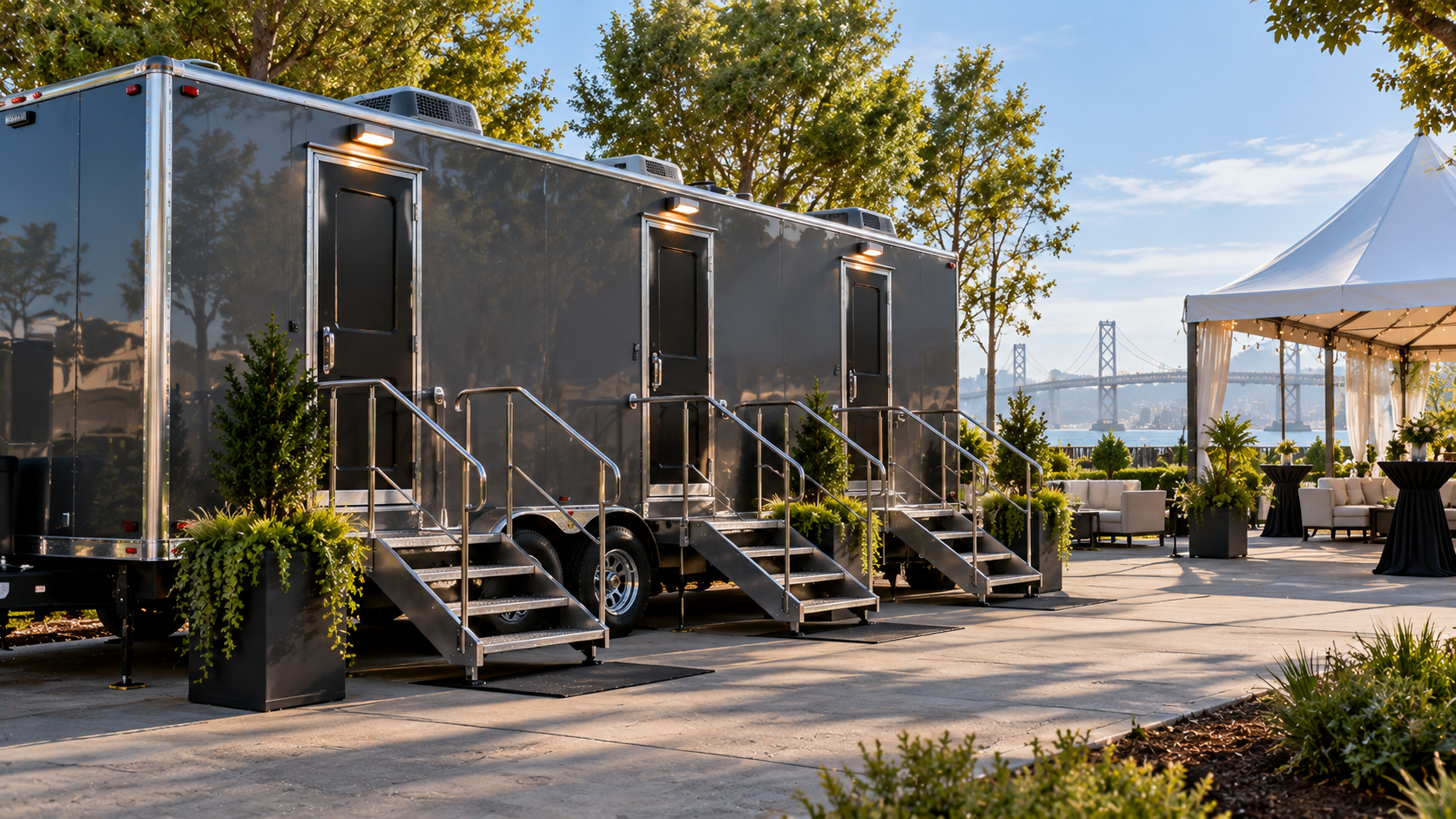 Black modular cabins with steps in a sunny outdoor event area beside a white canopy tent.