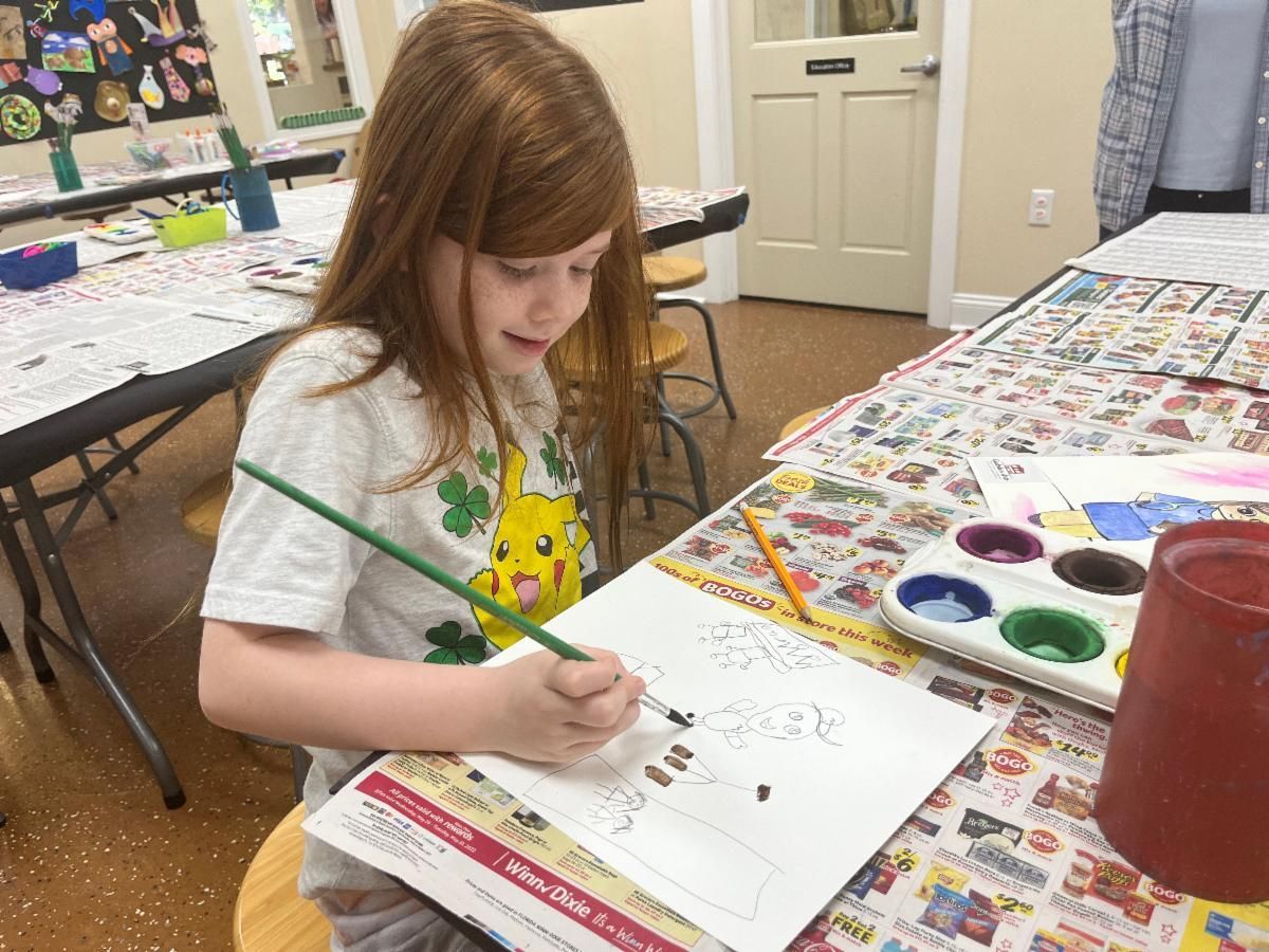 Child painting at a table with watercolor paints in a classroom.