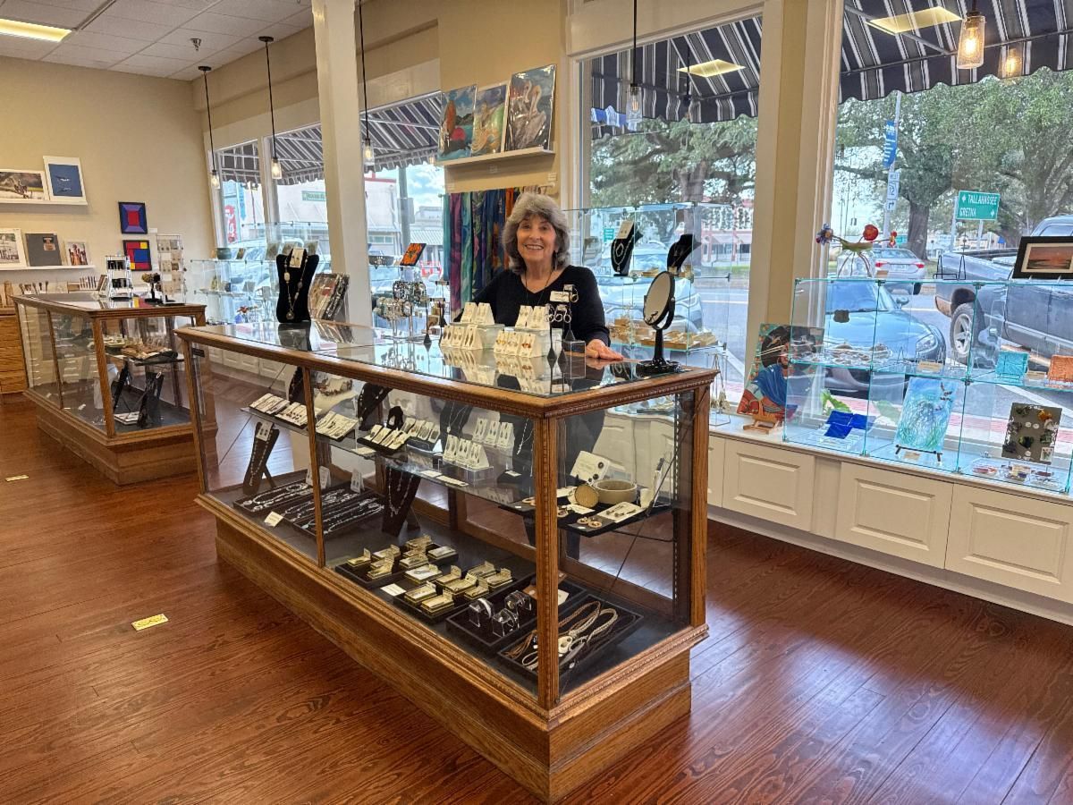 Bakery display case in a bright shop, with a person standing behind the counter.