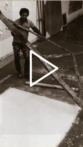 Person spreading mortar across a floor with a long tool in a room under renovation