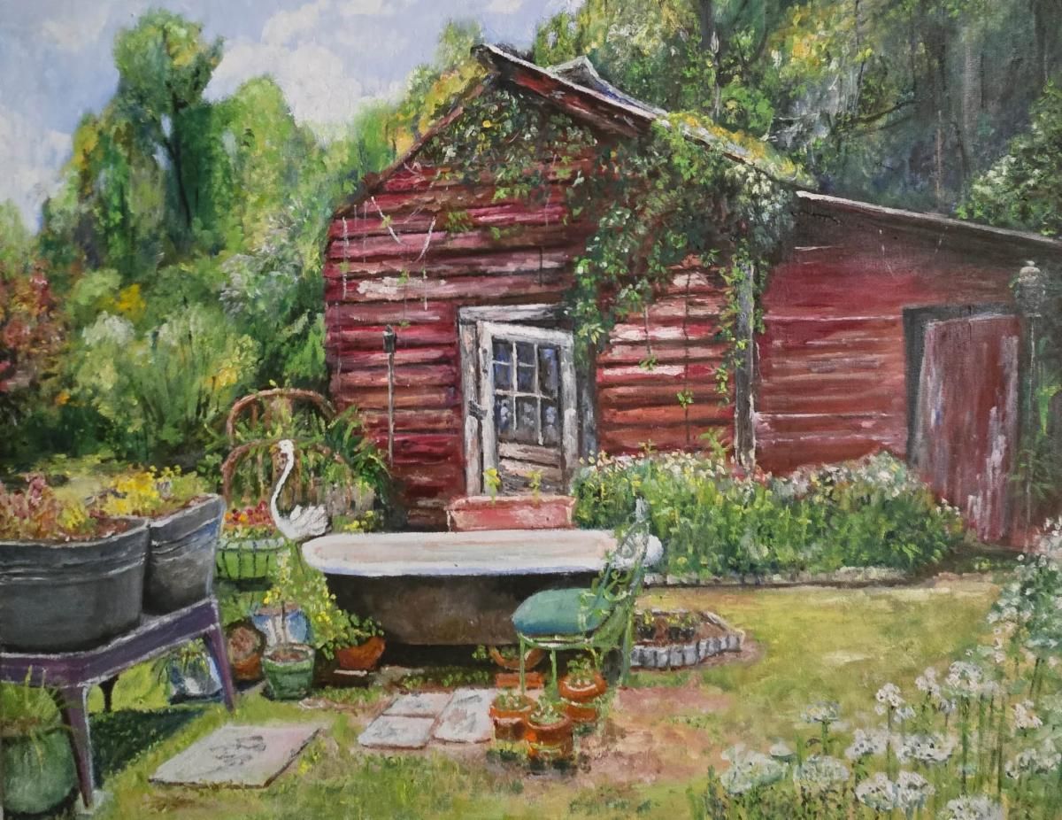 Red wooden shed in a lush garden with a white tub, potted plants, and flowers in the foreground