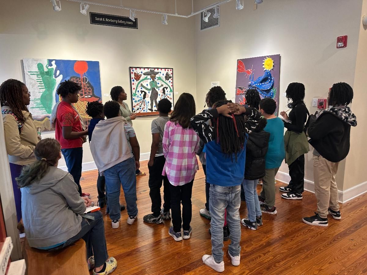 Students standing in an art gallery, viewing colorful paintings on the wall