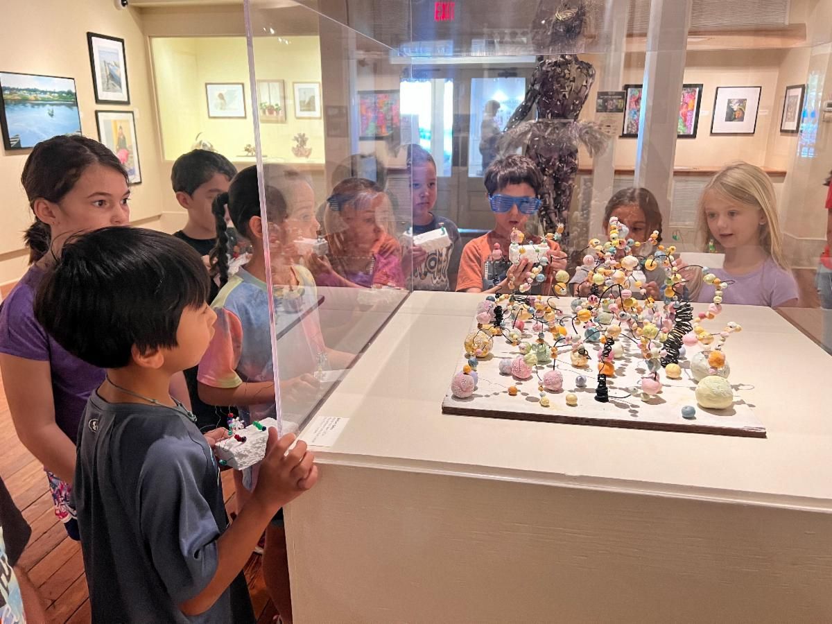Children viewing tiny figurines in a museum display case