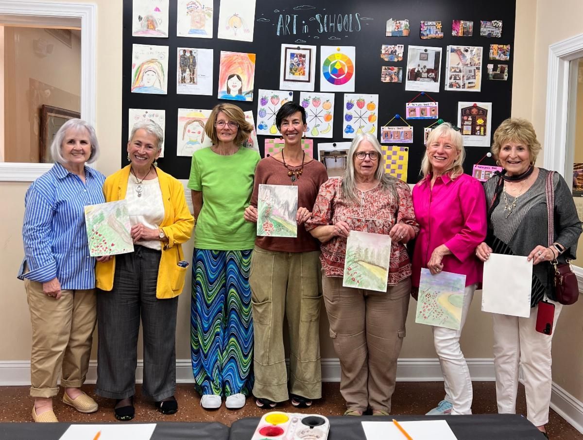 Seven people holding artwork in front of a wall display of colorful drawings in a gallery-like room
