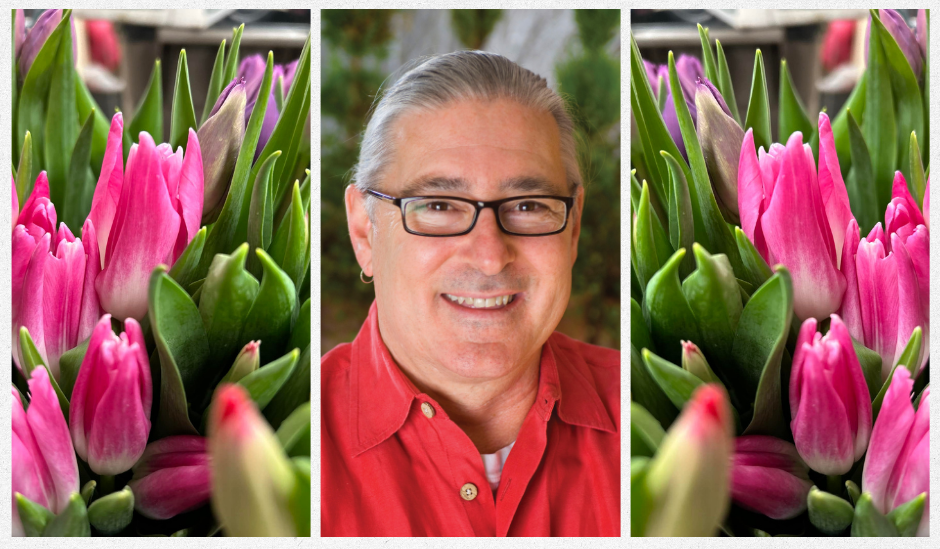 Smiling man in a red shirt between pink flower blooms on both sides