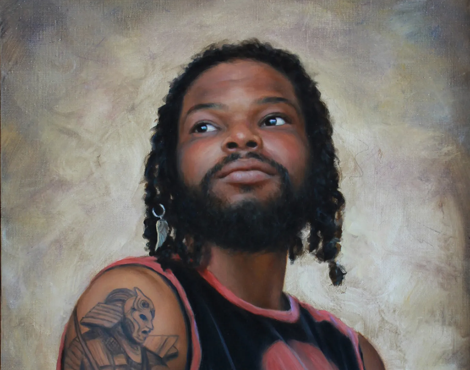 Portrait of a person with a beard and shoulder tattoo, wearing a black and red top against a soft painted backdrop