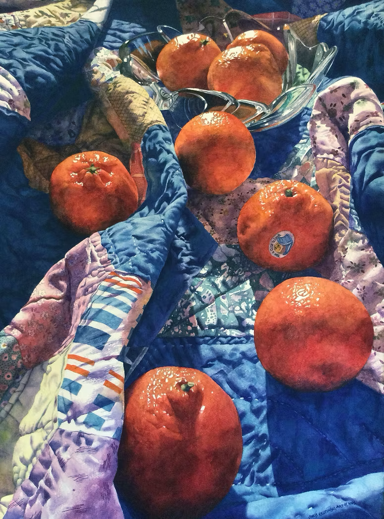 Apples and oranges scattered on a blue patterned quilted blanket