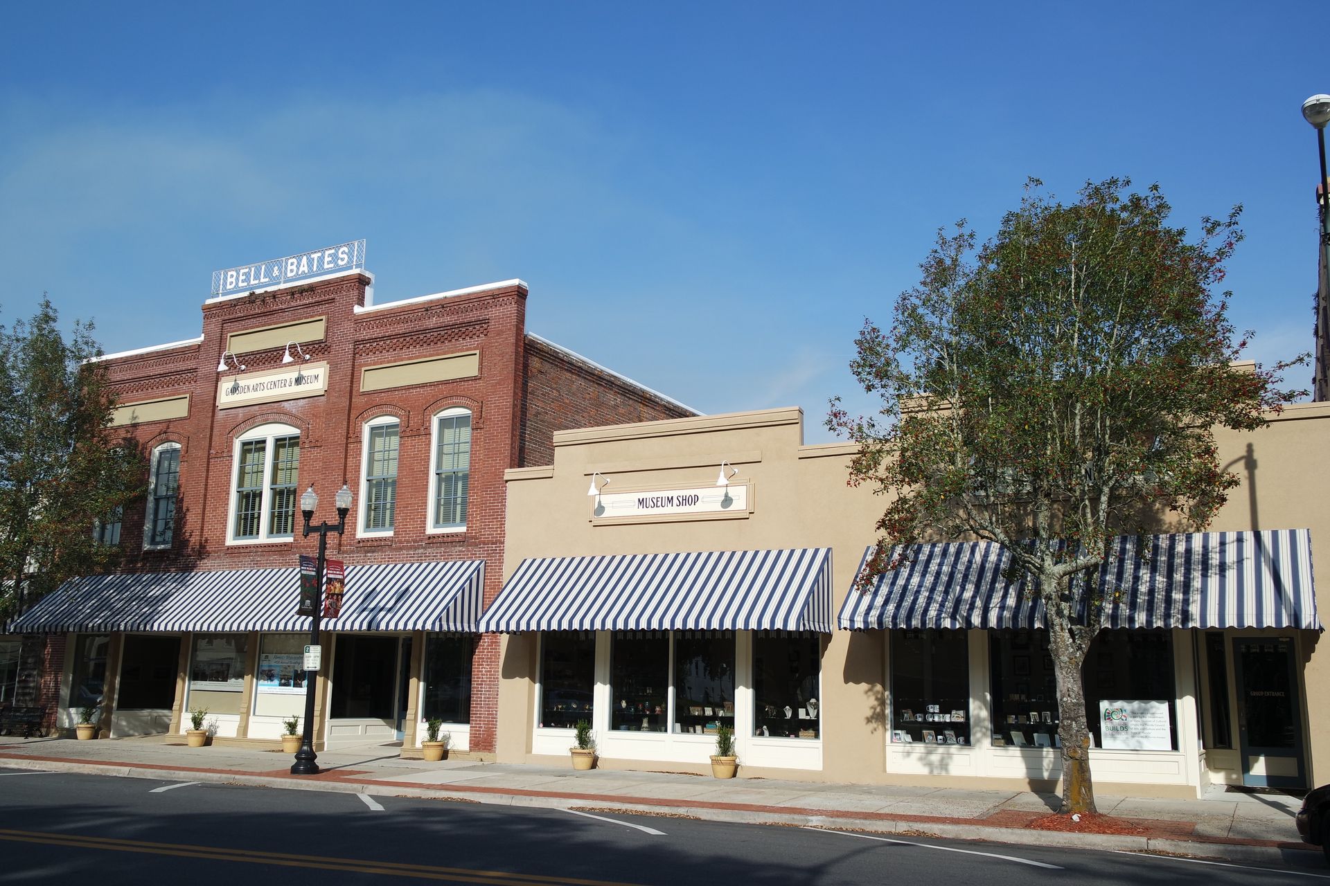 Historic brick storefronts with striped awnings on a sunny street.