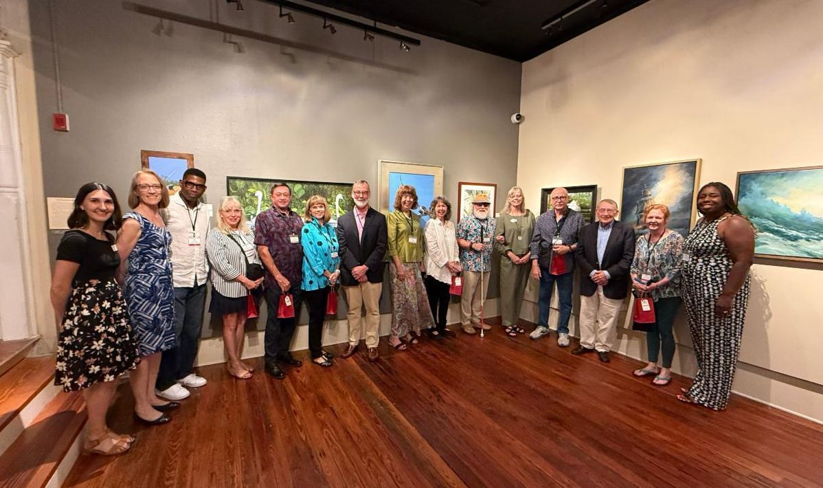 Group of people posing in an art gallery with colorful paintings on the walls