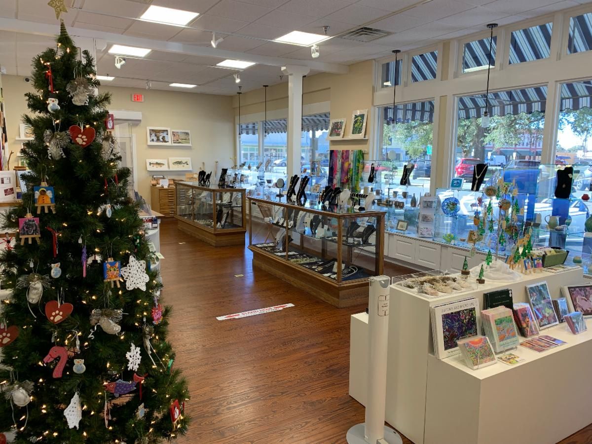 Holiday-decorated shop interior with Christmas tree, display tables, and front windows.