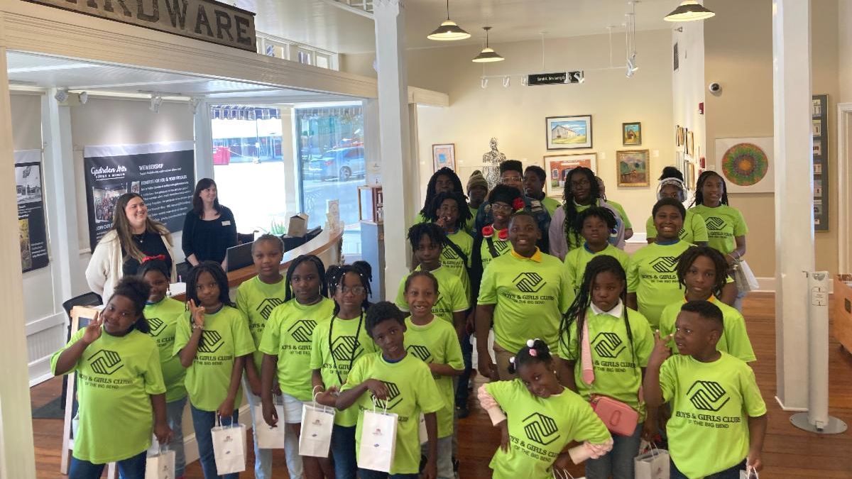 Group of children in bright green shirts posing indoors in a museum or gallery.