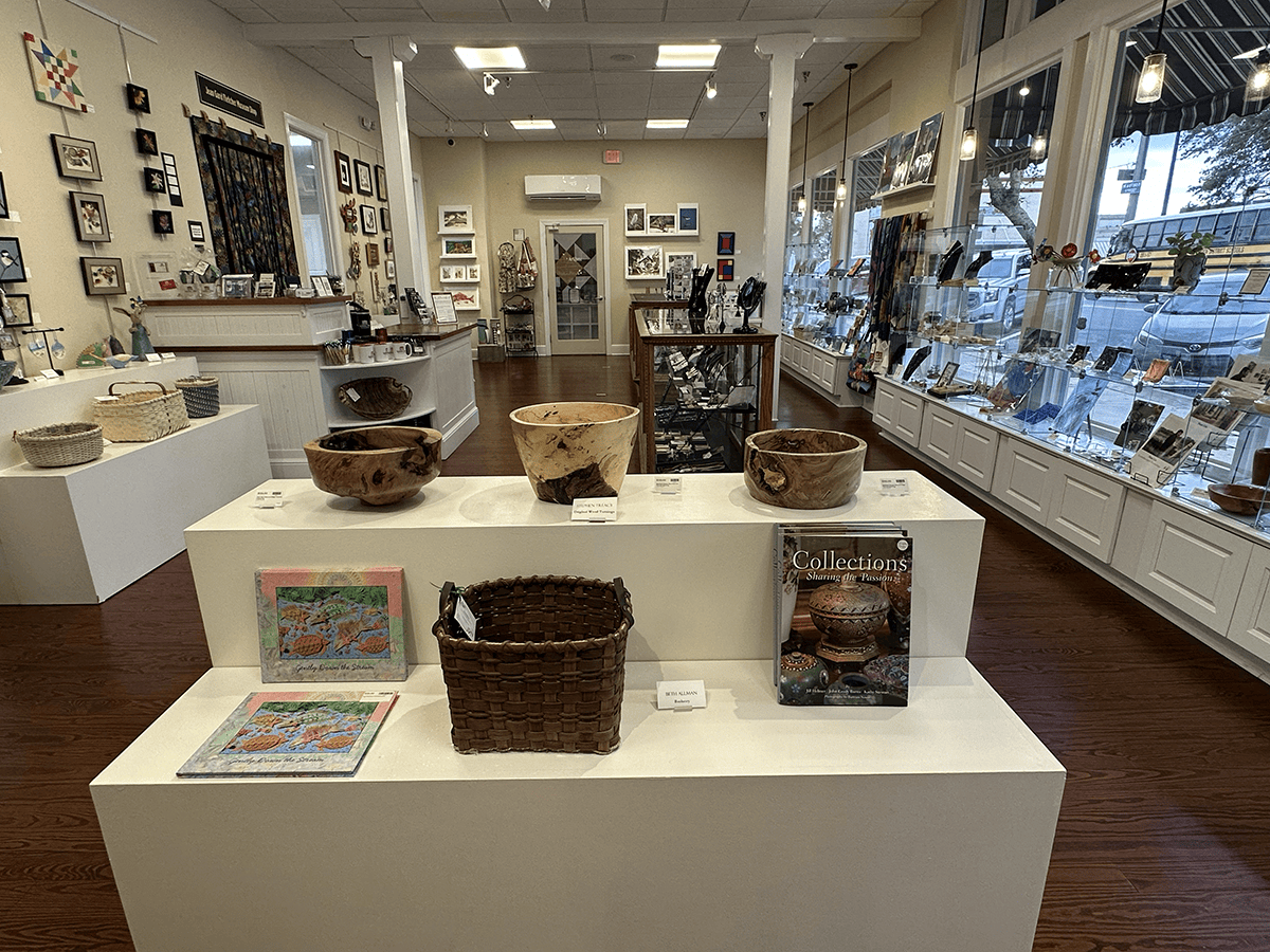 Boutique display of woven baskets on white pedestals in a bright gallery shop.