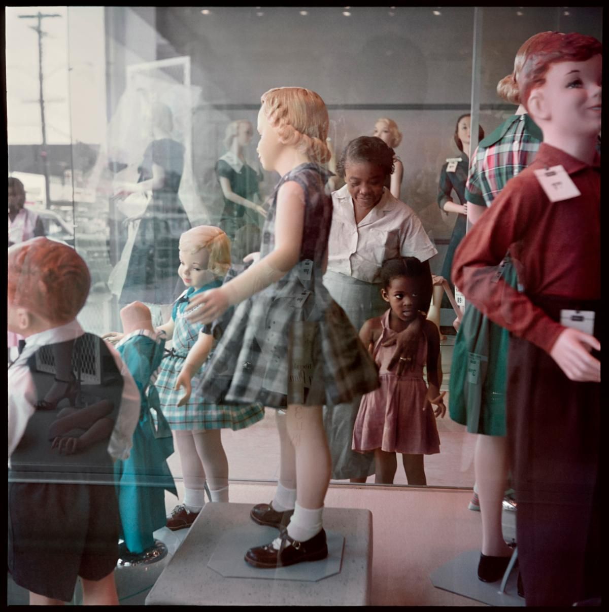 Mannequins of children in colorful outfits displayed in a store window