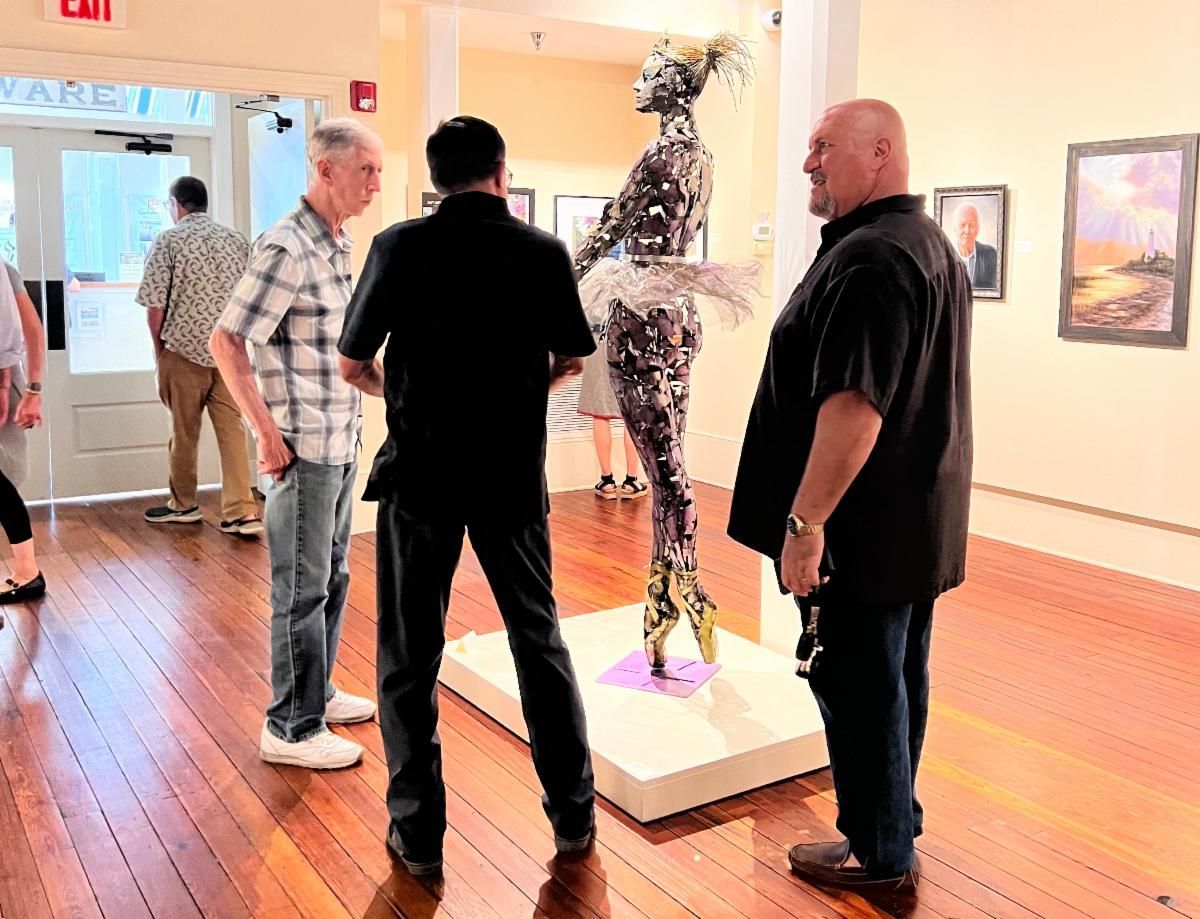 People viewing a metal sculpture in a bright art gallery