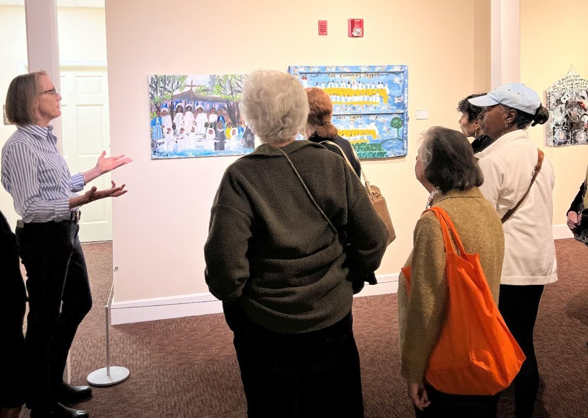 People viewing colorful artwork in a gallery, with one person gesturing toward the display