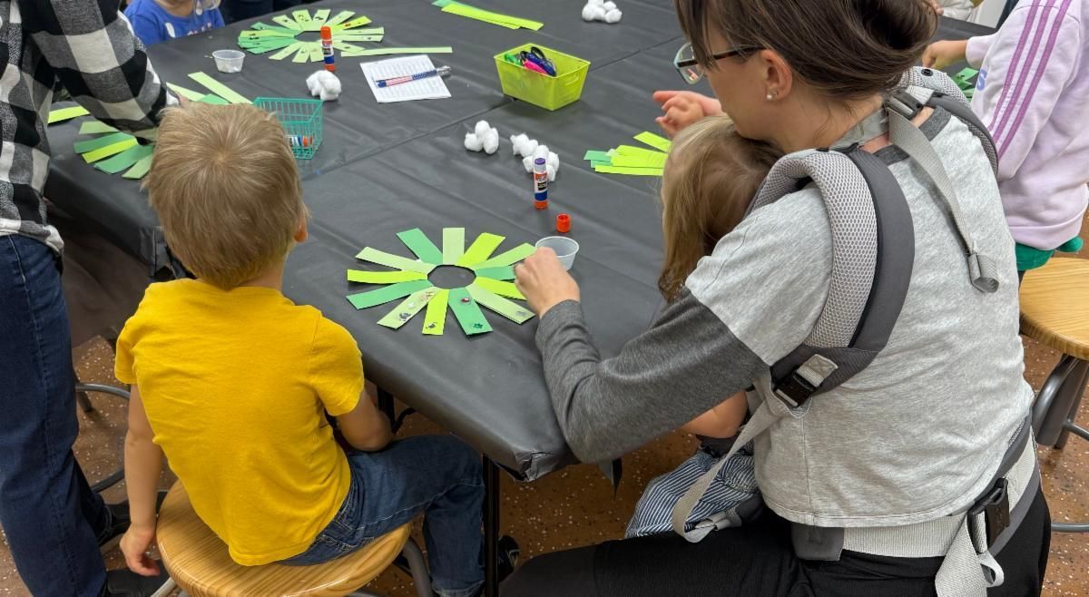 Children and an adult sit around a table making colorful paper flower crafts