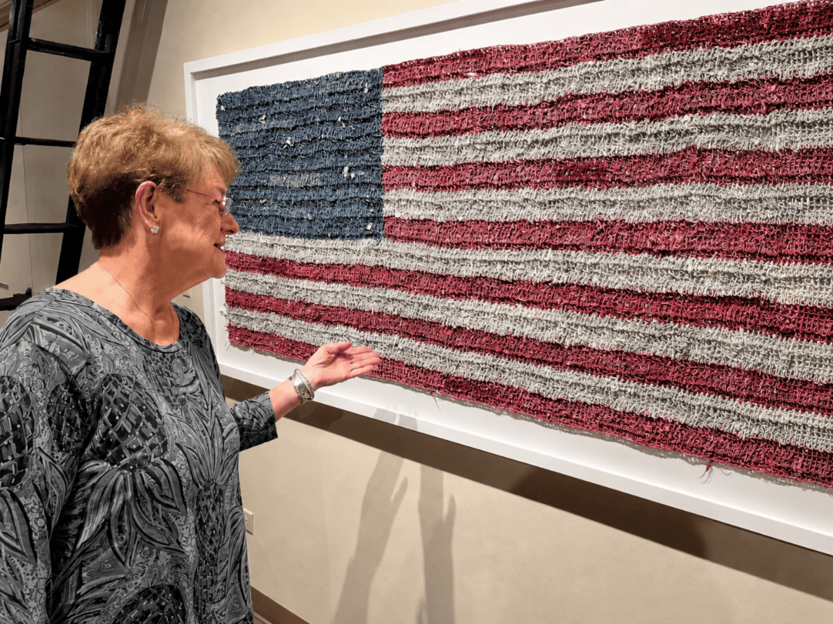 Woman viewing a textured American flag artwork mounted on a wall