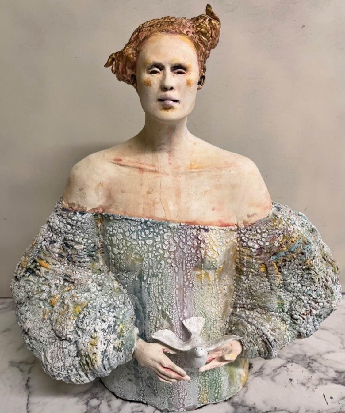 Portrait of a person in a textured off-shoulder garment, facing forward against a plain background